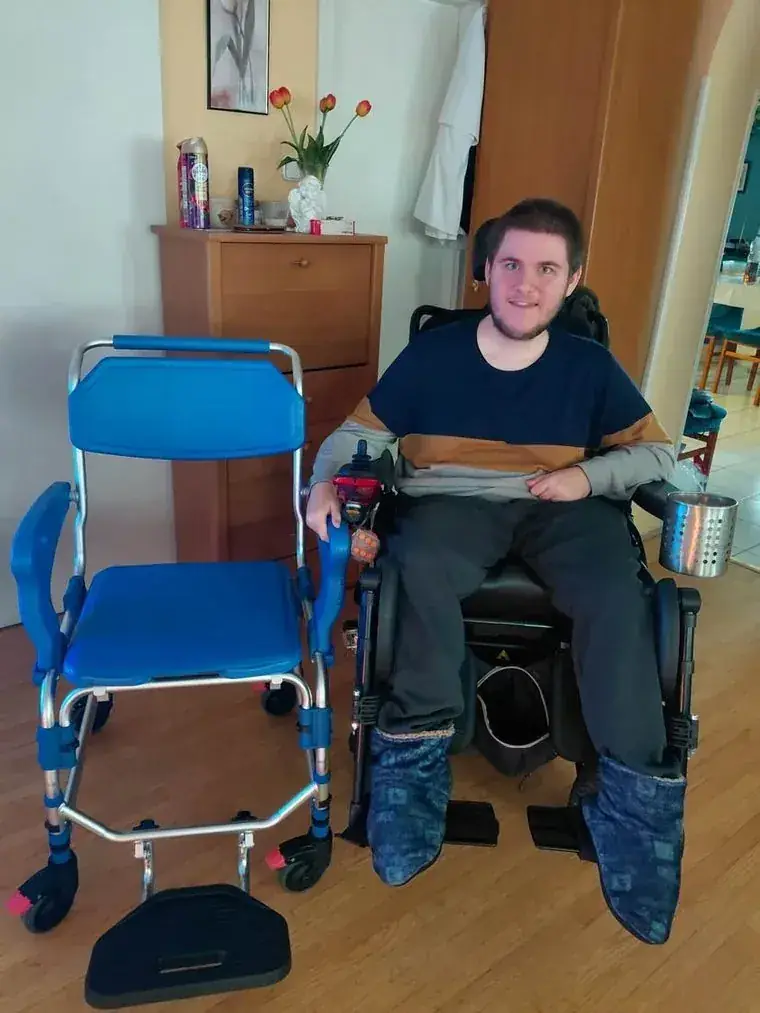 Levente a kerekesszékében az új fürdetőszék mellett